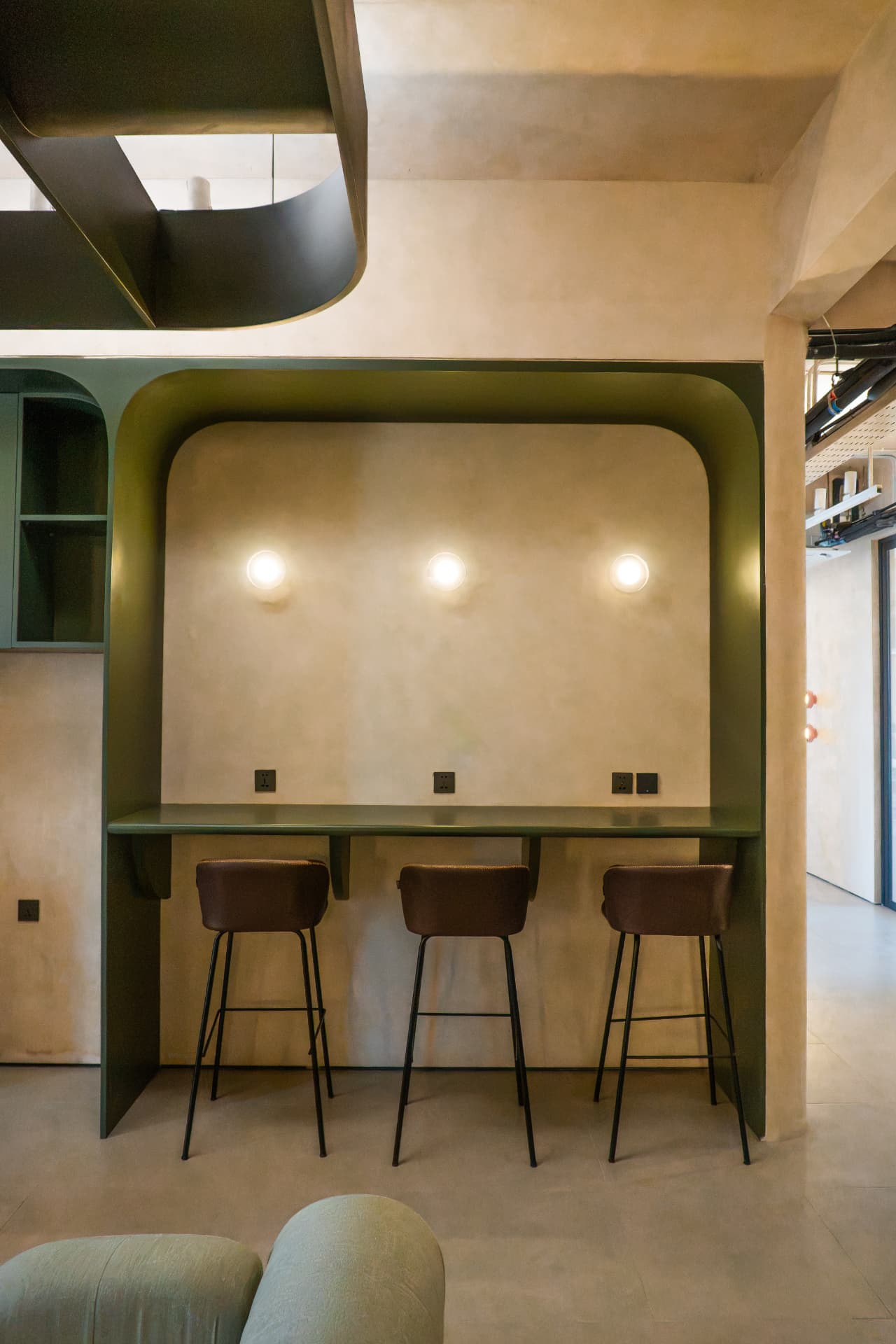 The kitchen and print corridor at Argil in Pererenan, with green joinery and bar seating