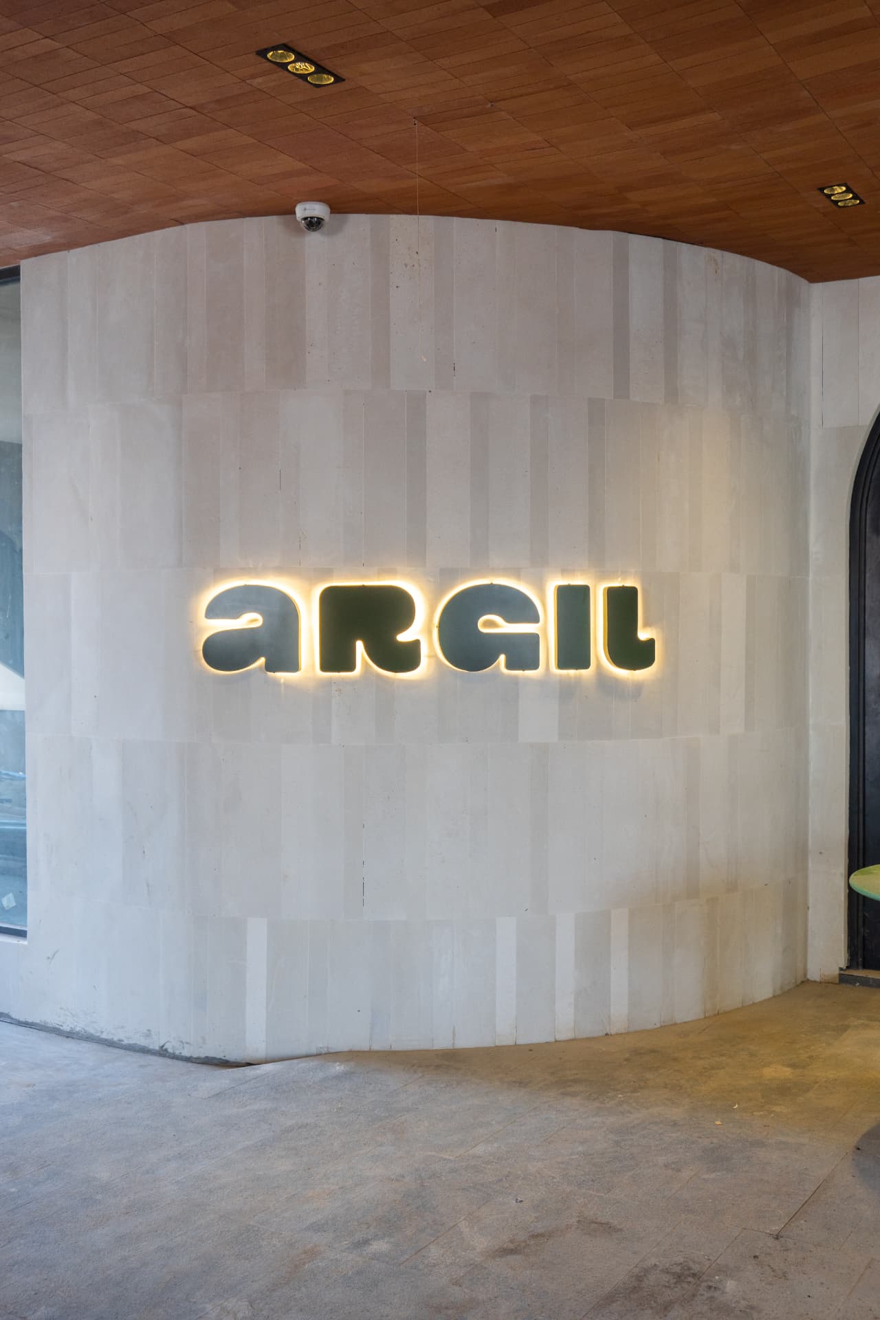 Reception and the member lockers at Argil in Pererenan, with a timber counter and clay-toned walls